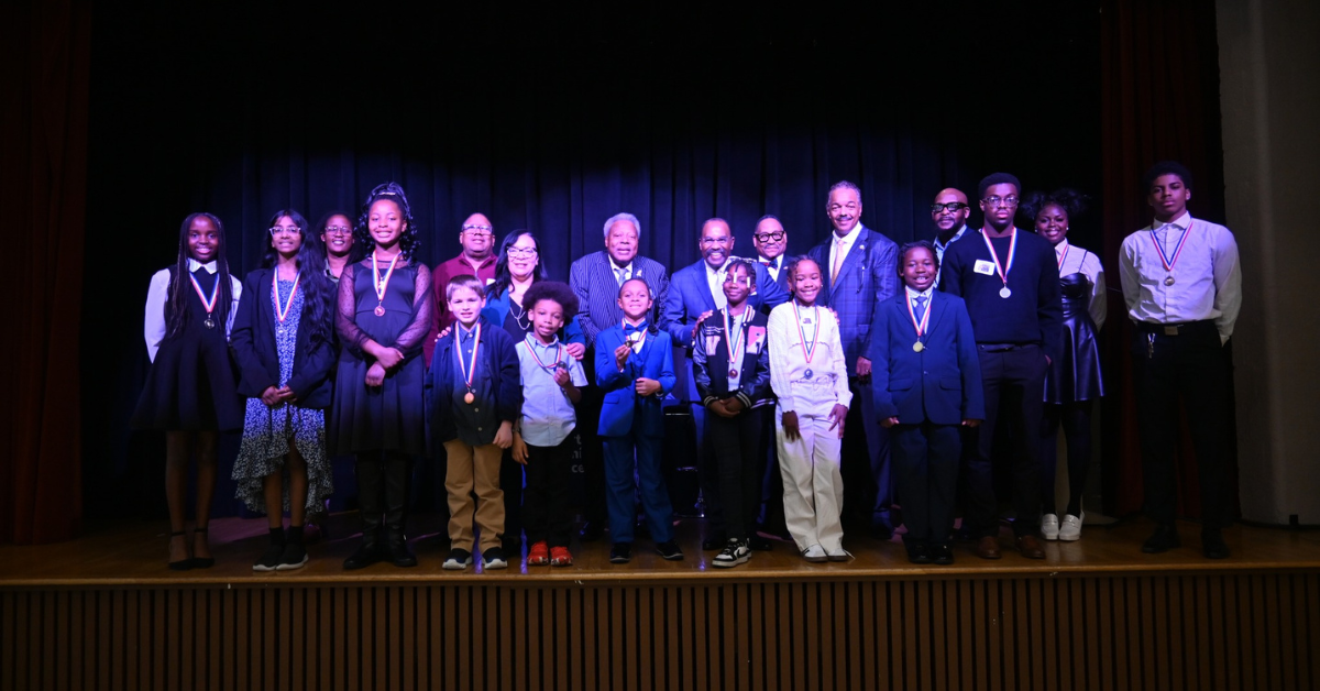 group of students on stage with medals and a blue background